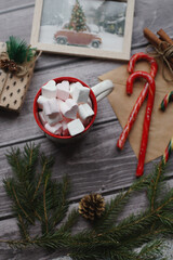 Cocoa with marshmallows, caramel candies, toys on a wooden photophone.