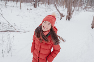Fototapeta na wymiar Happy Asian woman walking in winter snow forest smiling portrait. Cold weather hat and warm coat.