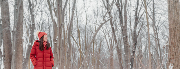 Winter lifestyle happy Asian woman walking in snow forest banner background looking up in joy. Girl...