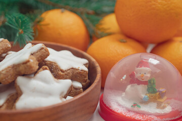 Winter background with Christmas tree branches, cones, Christmas toys, cookies and tangerines, with white space 