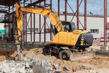 Professional demolition of reinforced concrete structures using industrial hydraulic hammer with excavator. Rods of metal fittings. Wreckage and crumbles of concrete.