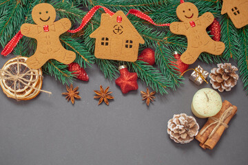 Winter background with Christmas tree branches, cones, Christmas toys and Christmas cookies, with black space for replicas