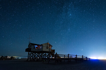 Pfahlbau an der Nordsee mit Milchstraße und Sterne bei Nacht