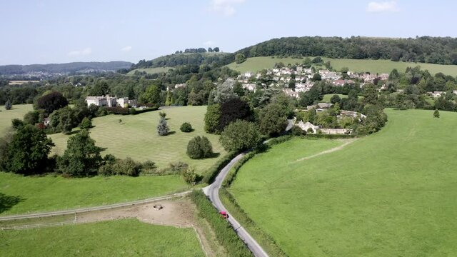 AERIAL - Stouts Hill, houses and hills in Uley, Cotswolds, England, wide forward