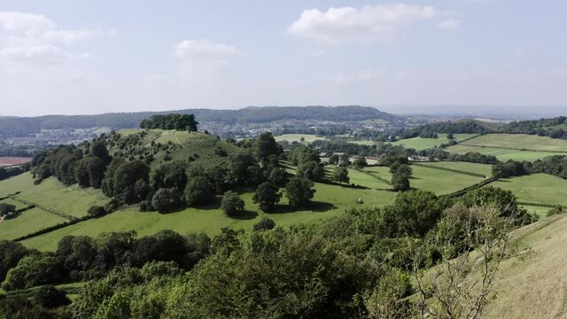 AERIAL - Couple walk their dog on a hill, Uley, Cotswolds, England, forward reveal