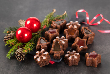 Holiday Christmas cacao cakes cookies in the shape of a tree, snowflakes, stars with marmalade on a serving board on a dark background