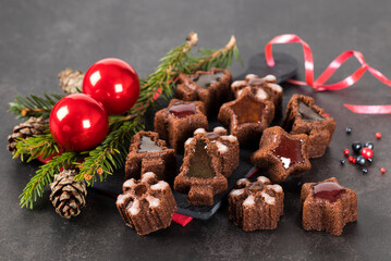Christmas dessert, chocolate little cakes cookies in the shape of a tree, snowflakes, stars with marmalade filling on a serving board on a dark gray background