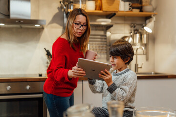mother and son looking for recipes on digital tablet in kitchen
