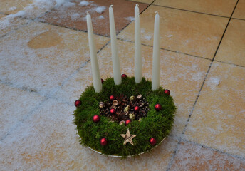 Advent candlestick made of moss and cones. shiny red balls and white four candles. table decoration...