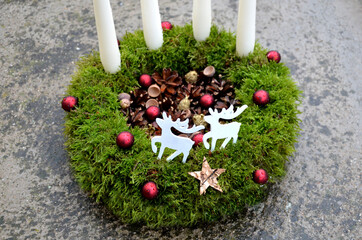 Advent candlestick made of moss and cones. shiny red balls and white four candles. table decoration...
