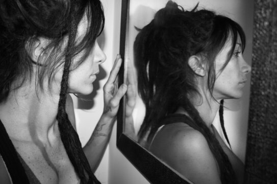 A woman in the mirror magically reflects a different image. Surreal concept, communication and psychology.