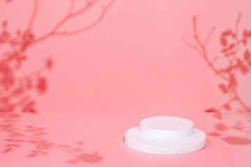 Abstract minimal nature scene - empty stage and circle podium on pink background and soft shadows of rose flowers and leaves. Pedestal for cosmetic product and packaging mockups display presentation