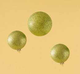 Minimal Christmas, party, New Year geometrical composition. Glitter green baubles or balls   decorations on yellow color background. Minimalism. Creative Christmas, New Year, party, concept.