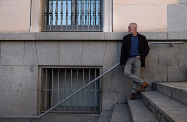 Adult man in suit standing on stairway in city against stone wall