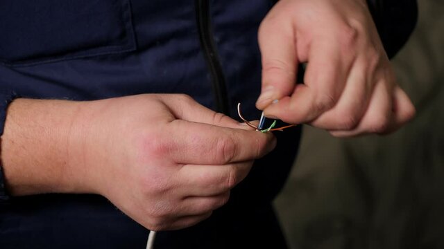 Stripping wires and removing insulation from the live wire of the Internet cable. Close-up of person hand with pliers cutting cable.