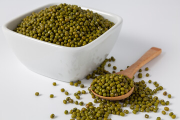 mung bean in bowl and wood spoon on pile of mung bean white background studio shot