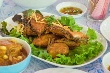 Crispy fried tilapia slices placed in a white plate. Select the focus and blur according to the lens character.