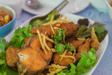 Crispy fried tilapia slices placed in a white plate. Select the focus and blur according to the lens character.