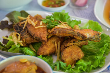 Crispy fried tilapia slices placed in a white plate. Select the focus and blur according to the lens character.