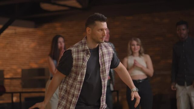 A male bowling player throws a ball with the support of friends and rejoices by knocking out a striking