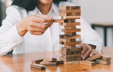 The business man's hand is planning a business strategy, the businessman plays the wooden block tower, Plans and strategies in the concept of a risky business