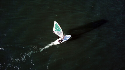 Surfboarding on a city urban river. Drone aerial photo.