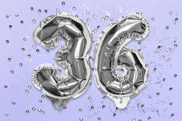 Silver foil balloon number, digit thirty six on a lilac background with sequins. Birthday greeting card with inscription 36. Top view. Numerical digit. Celebration event, template.