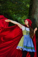 Little Red Riding Hood's cape flying out behind her while she is walking in the Black Forest of Germany on a fall day.