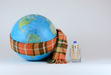 Earth globe wrapped in scarf, medical thermometer, pills and medicines in glass. Ecological concept on the theme of saving planet earth, global epidemic, worldwide diseases. Saving environment, save c
