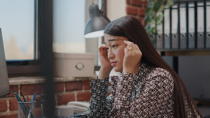 Close up of employee with headache rubbing temples to work on business project and strategy. Asian...