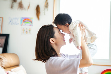 母親に抱き上げられて笑顔の赤ちゃん