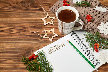 Christmas composition of open blank notepad, coffee cup, scarf and fir branches on wooden background