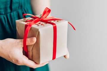 Female hands holding Merry Christmas gift with red ribbon , woman prepare surprise new year winter merry handmade holiday present concept