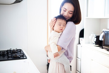 眠っている赤子を抱きしめる母親