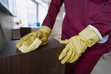 Housecleaner in rubber gloves dusting speaker box