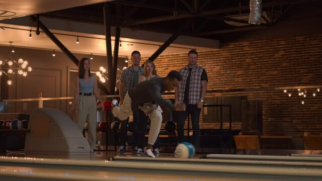 General Plan Black Male Bowling Player Throws Ball With Support From Friends And Rejoices By Knocking Out A Strip