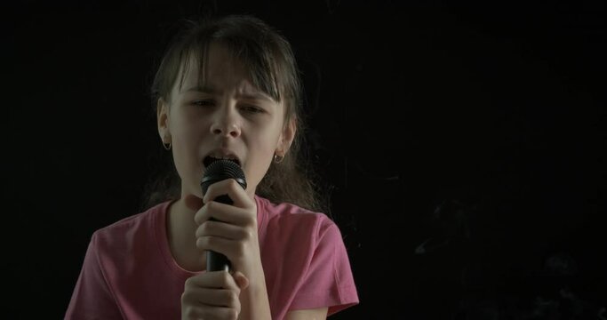 The Teenager Sings. Girl Teenager Girl Singing Into A Microphone On A Dark Background.