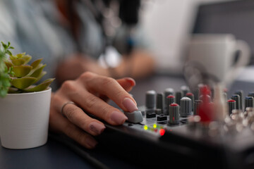 Closeup of hand using volume slider on audio mixing equipment. Person working with digital sound...