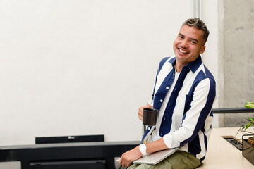 Cheerful man with coffee and laptop sitting on table