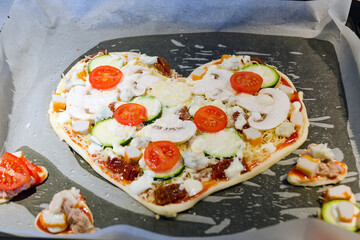 Heart shaped pizza with tomatoes, vegetables and cheese for Valentine's Day on background. Creative food concept of romantic love. Top view, flat lay.