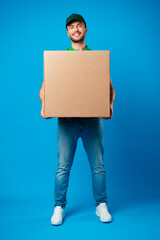 Delivery man with box in studio against blue background