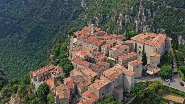 Gourdon France Aerial v2 birdseye view drone hovering around high altitude mountain clifftop old defensive stone castle ruins and village - July 2021