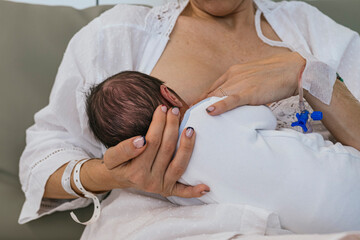 Obraz na płótnie Canvas Mother breastfeeding her newborn after giving birth in a hospital. Maternity concept.
