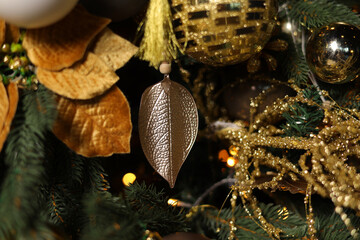 Golden Christmas toy hanging on the Christmas tree. Golden bokeh lights on a festive background. The concept of home comfort and festive mood. Decorate the Christmas tree