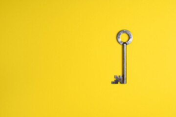 Old door key isolated on yellow background. Flat lay.