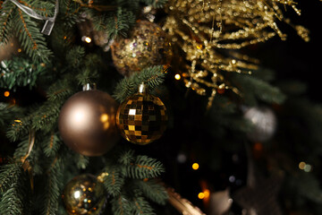A Christmas tree decorated with golden shiny Christmas balls. Magical cozy details, festive winter background. Magical Bokeh effect. Festive background of winter holidays