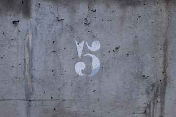 weathered concrete wall with the number 5 painted white