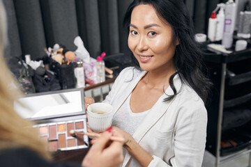 Elegant woman in white clothes enjoying great time in modern bright salon