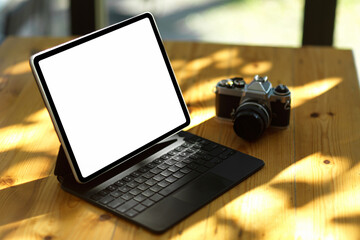 Tablet computer in white screen mockup and camera on table