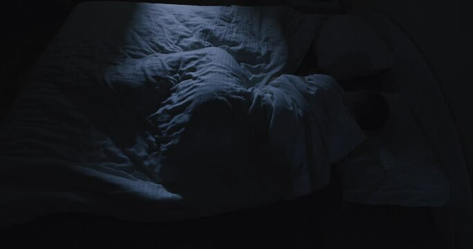 Man tossing and turning in a bed at night, cannot sleep, view from above